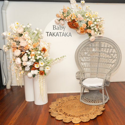 Decorative floral arrangements with a wicker chair on a wooden floor. baby shower backdrop, neutral floral backdrop, elegant event styling, Brisbane party hire, floral arch setup, engagement backdrop, birthday backdrop hire, custom event decor, neutral baby shower theme, white arch floral arrangement