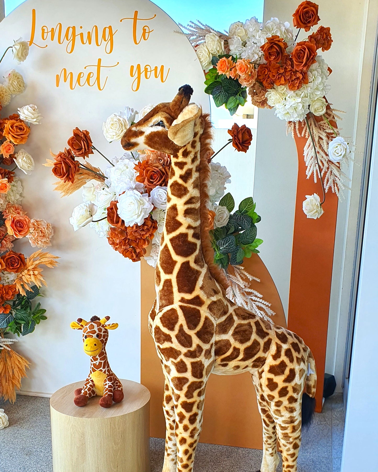 Decorative display with two giraffe plush toys and an arrangement of orange, white, and green flowers under a white and orange arch. Prop hire, Prop hiring, Prop hire, event stylists Brisbane, brisbane event styling, brisbane event styling, event stylist Brisbane, Brisbane Wedding, Gold Coast Wedding, Floral Styling, Lush & Lavish Events, Brisbane Tablescape, Gold Coast Tablescapes, Brisbane Candle Hire
