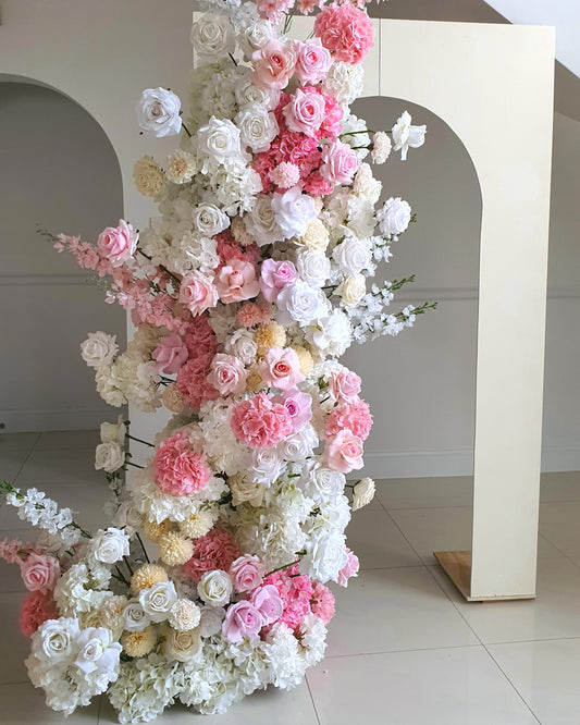 Vertical floral arrangement with white, pink, and yellow flowers against a plain background and archway. Prop hire, Prop hiring, Prop hire, event stylists Brisbane, brisbane event styling, brisbane event styling, event stylist Brisbane, Brisbane Wedding, Gold Coast Wedding, Floral Styling, Lush & Lavish Events, Brisbane Tablescape, Gold Coast Tablescapes, Brisbane Candle Hire