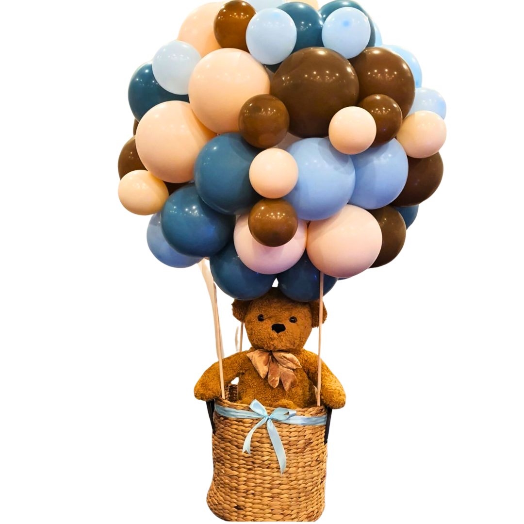 Balloon cluster in blue, brown, and peach resembling a hot air balloon, with a teddy bear in a woven basket. Prop hire, Prop hiring, Prop hire, event stylists Brisbane, brisbane event styling, brisbane event styling, event stylist Brisbane, Brisbane Wedding, Gold Coast Wedding, Floral Styling, Lush & Lavish Events, Brisbane Tablescape, Gold Coast Tablescapes, Brisbane Candle Hire