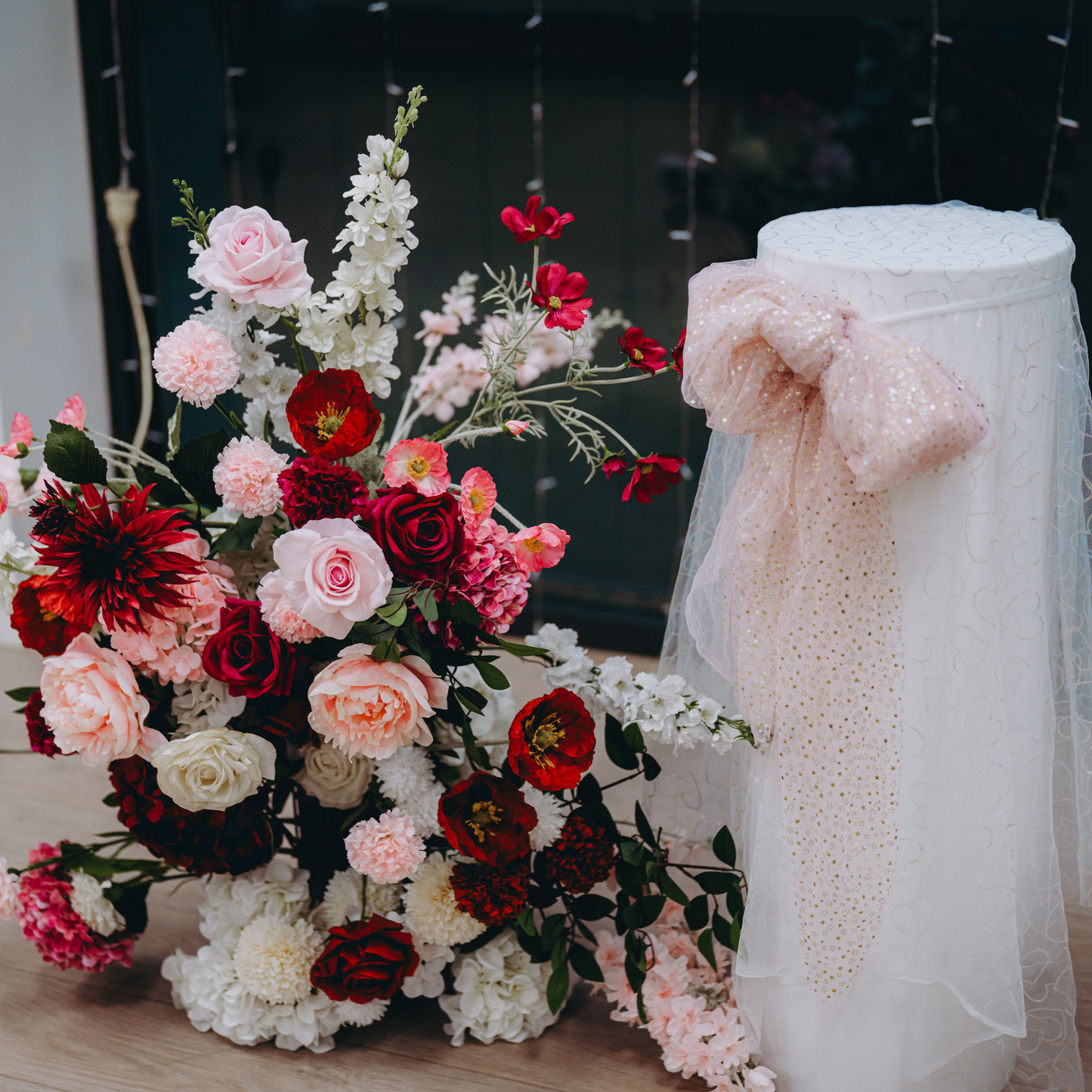 Floral arrangement with red, pink, and white flowers, next to a white stand with a glittery pink bow. Prop hire, Prop hiring, Prop hire, event stylists Brisbane, brisbane event styling, brisbane event styling, event stylist Brisbane, Brisbane Wedding, Gold Coast Wedding, Floral Styling, Lush & Lavish Events, Brisbane Corporate Styling, Gold Coast Corporate Styling, Brisbane Brand Activation