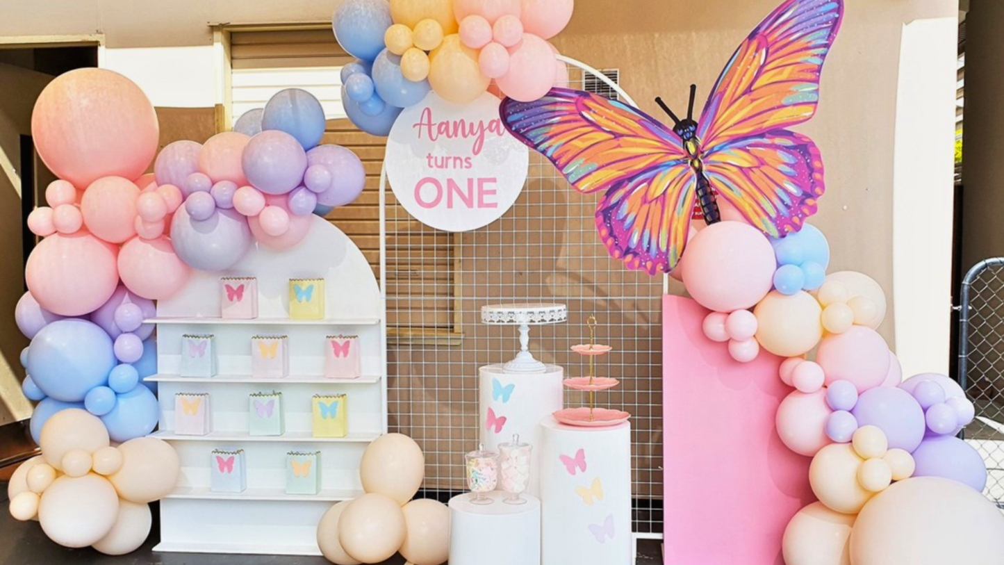 Colorful first birthday party setup with pastel balloons, a large butterfly decoration, and a display spelling ‘ANYA’ for a one-year-old’s celebration Prop hire, Prop hiring, Prop hire, event stylists Brisbane, brisbane event styling, brisbane event styling, event stylist Brisbane, Brisbane Wedding, Gold Coast Wedding, Floral Styling, Lush & Lavish Events