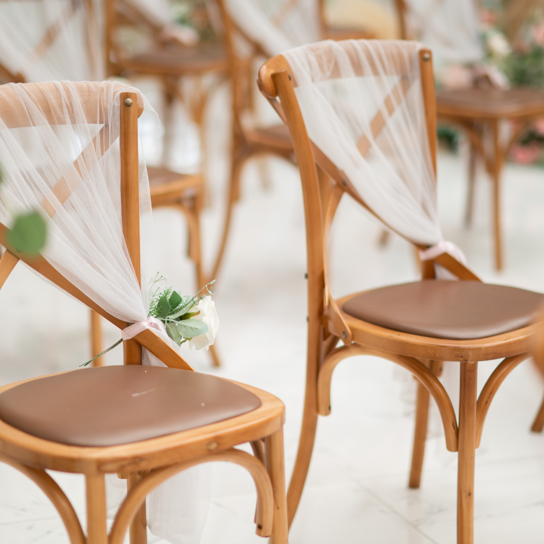 Wooden chairs with brown seats are decorated with white tulle fabric and small floral arrangements. Prop hire, Prop hiring, Prop hire, event stylists Brisbane, brisbane event styling, brisbane event styling, event stylist Brisbane, Brisbane Wedding, Gold Coast Wedding, Floral Styling, Lush & Lavish Events