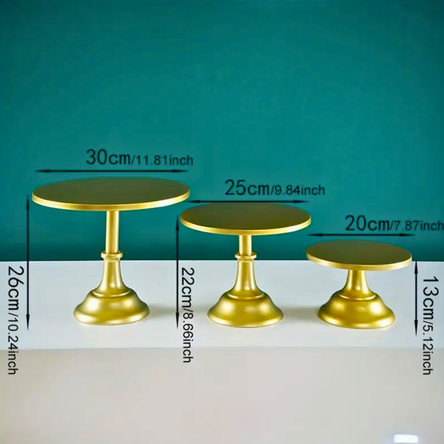 Three gold cake stands with measurements on a teal and white background. white cake stand, cake stand set, dessert display, tiered cake stand, wedding cake stand, birthday cake stand, cupcake stand, party hire Brisbane, party hire Gold Coast, cake table display, event hire Brisbane, event hire Gold Coast, celebration tableware, elegant cake stand, white dessert stand, cake display hire, table centrepiece stand, cake presentation, party styling Brisbane, party styling Gold Coast