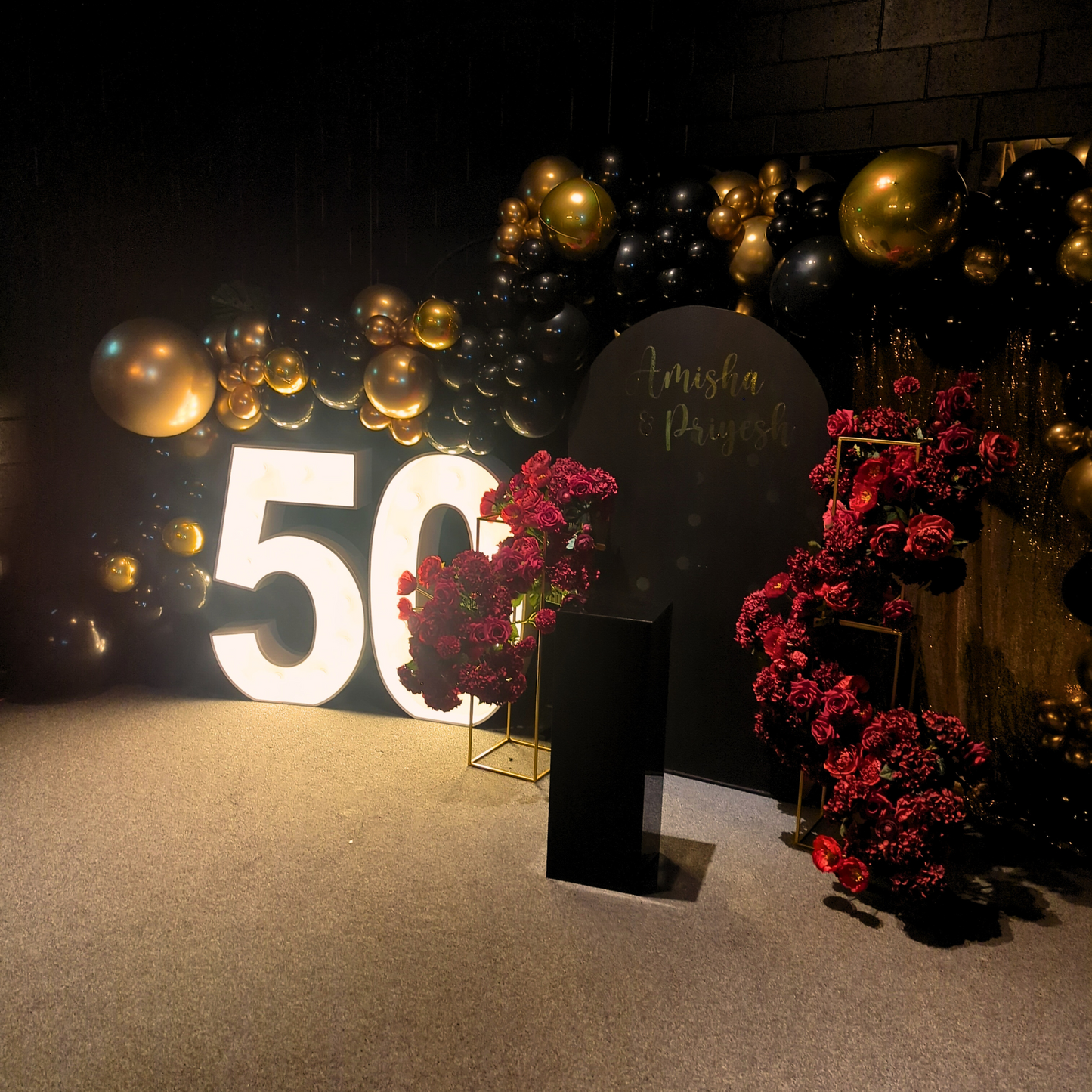 White '50' with gold and black balloons, red flowers and greenery on a pedestal with 'Amish and Priyesh' sign, for a 50th birthday party. Prop hire, Prop hiring, Prop hire, event stylists Brisbane, brisbane event styling, brisbane event styling, event stylist Brisbane, Brisbane Wedding, Gold Coast Wedding, Floral Styling, Lush & Lavish Events, Brisbane Tablescape, Gold Coast Tablescapes, Brisbane Candle Hire
