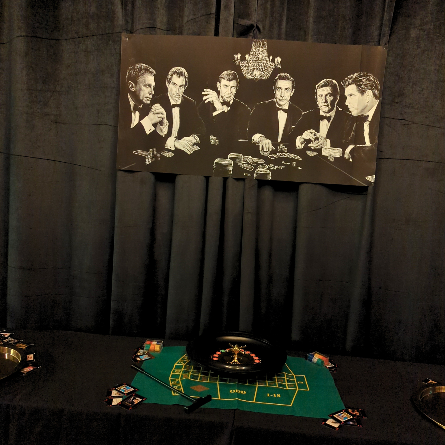 Dessert table with dark curtains, James Bond poster, roulette wheel centerpiece, playing card designs, and themed desserts for a casino event. Prop hire, Prop hiring, Prop hire, event stylists Brisbane, brisbane event styling, brisbane event styling, event stylist Brisbane, Brisbane Wedding, Gold Coast Wedding, Floral Styling, Lush & Lavish Events, Brisbane Tablescape, Gold Coast Tablescapes, Brisbane Candle Hire