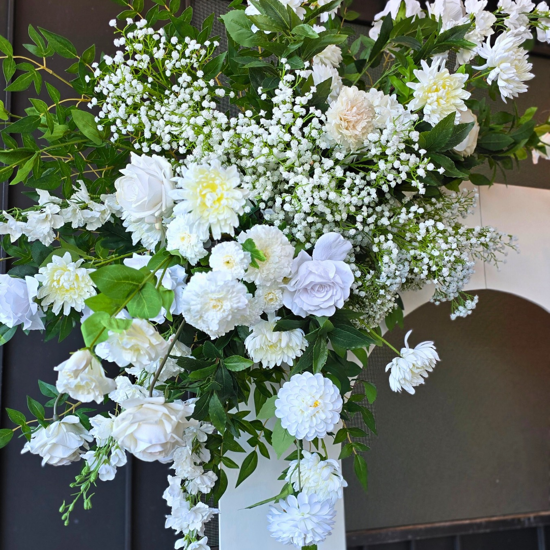 Bouquet of white flowers with green leaves against a neutral background. engagement party backdrop, floral engagement backdrop, romantic event styling, wedding decor hire, proposal backdrop hire, Brisbane event hire, elegant floral arch, custom event backdrop, pre-wedding decorations, luxe engagement party setup