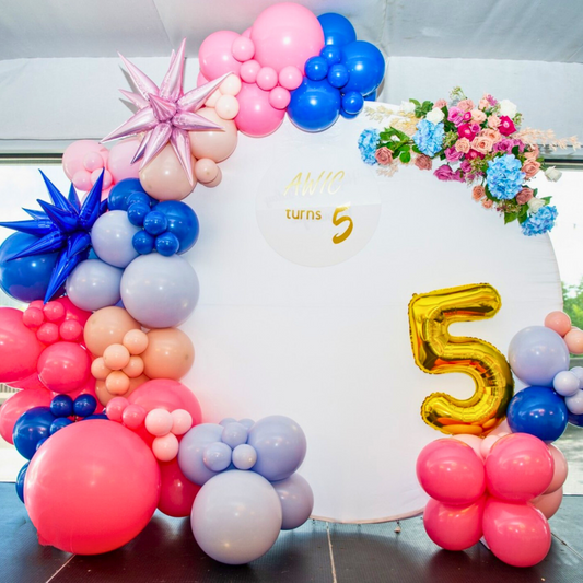 A large white backdrop features a colorful balloon arrangement, floral decorations, and the text "AWIC turns 5." A large metallic number 5 balloon completes the celebratory design. Prop hire, Prop hiring, Prop hire, event stylists Brisbane, brisbane event styling, brisbane event styling, event stylist Brisbane, Brisbane Wedding, Gold Coast Wedding, Floral Styling, Lush & Lavish Events, Brisbane Corporate Styling, Gold Coast Corporate Styling, Brisbane Brand Activation