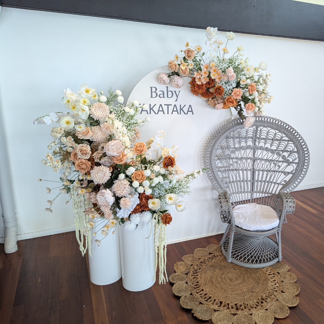 Decorative floral arrangement with a chair and 'Baby TAKATAKA' sign on a white wall. baby shower backdrop, neutral floral backdrop, elegant event styling, Brisbane party hire, floral arch setup, engagement backdrop, birthday backdrop hire, custom event decor, neutral baby shower theme, white arch floral arrangement