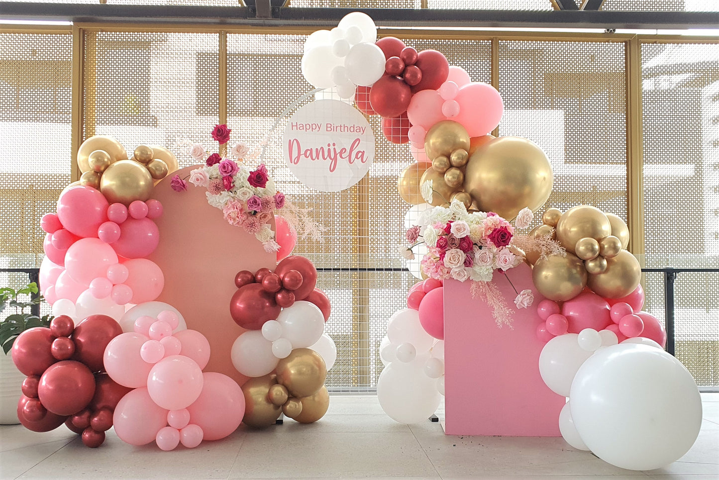 Gorgeous birthday party backdrop with pink, white, and gold balloons and floral arrangements, featuring a sign that says "Happy Birthday Danijela." Styled by Lush and Lavish Events in Brisbane.