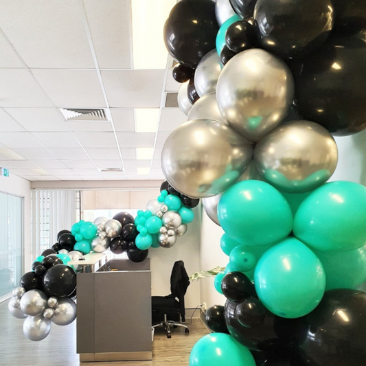 Black, silver, and teal balloons create a festive atmosphere in an office space. The balloons are clustered together and appear to be floating near the ceiling. Prop hire, Prop hiring, Prop hire, event stylists Brisbane, brisbane event styling, brisbane event styling, event stylist Brisbane, Brisbane Wedding, Gold Coast Wedding, Floral Styling, Lush & Lavish Events, Brisbane Corporate Styling, Gold Coast Corporate Styling, Brisbane Brand Activation