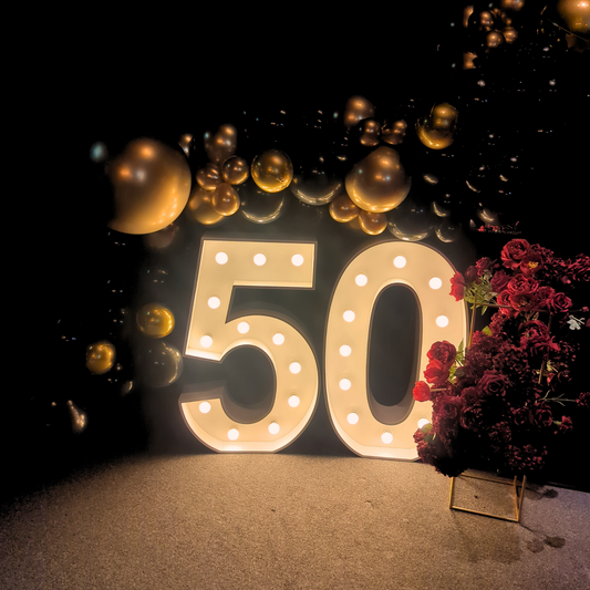 Illuminated '50' with golden balloons, red flowers, and a warm, dimly lit ambiance. Prop hire, Prop hiring, Prop hire, event stylists Brisbane, brisbane event styling, brisbane event styling, event stylist Brisbane, Brisbane Wedding, Gold Coast Wedding, Floral Styling, Lush & Lavish Events, Brisbane Tablescape, Gold Coast Tablescapes, Brisbane Candle Hire