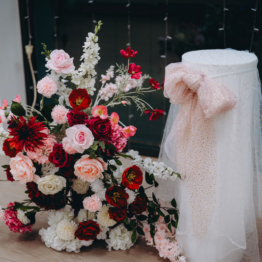 Floral arrangement with red, pink, and white flowers, next to a white stand with a glittery pink bow. Prop hire, Prop hiring, Prop hire, event stylists Brisbane, brisbane event styling, brisbane event styling, event stylist Brisbane, Brisbane Wedding, Gold Coast Wedding, Floral Styling, Lush & Lavish Events, Brisbane Corporate Styling, Gold Coast Corporate Styling, Brisbane Brand Activation