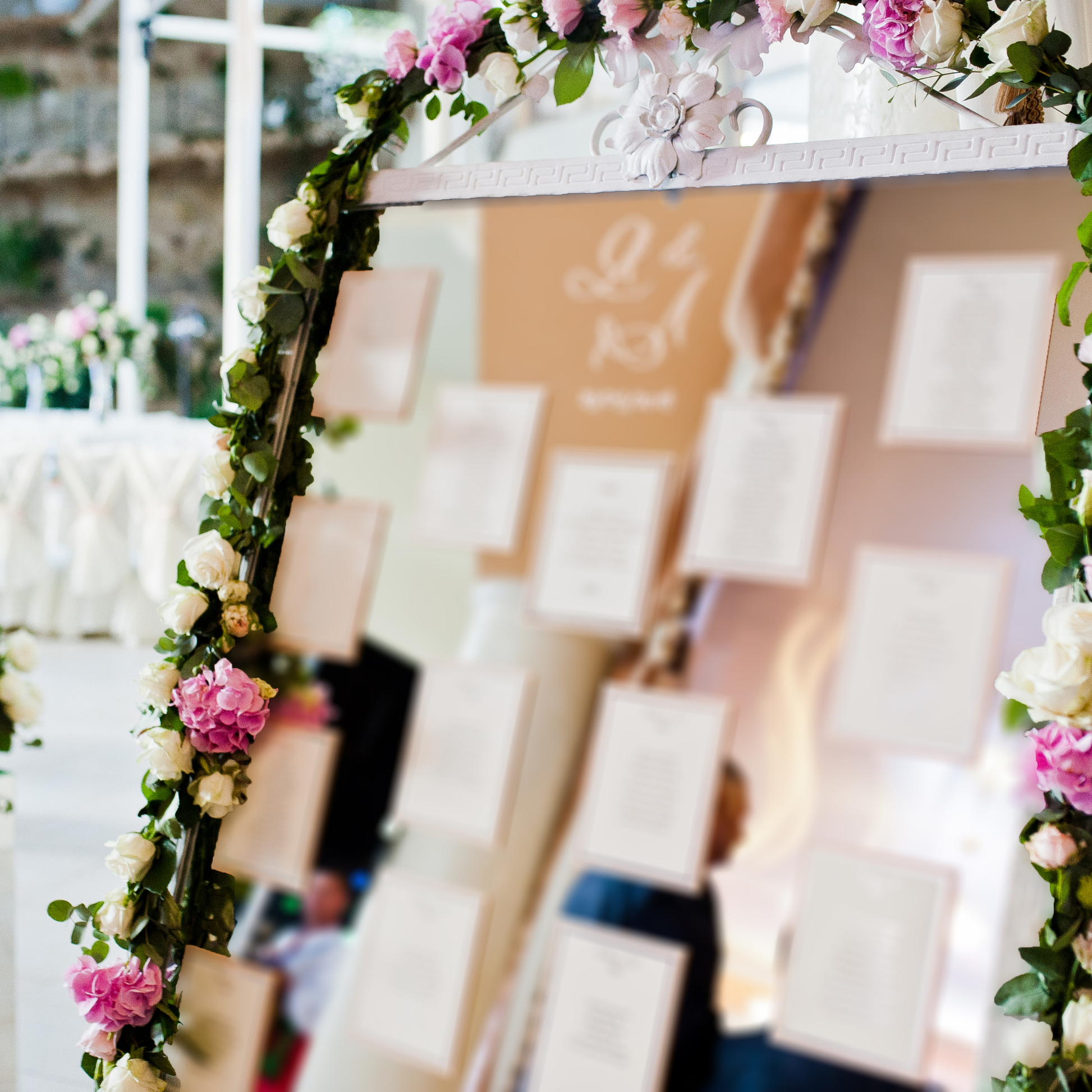 arge mirror decorated with pink and white flowers, displaying a seating chart for an event, with a blurred background of tables and chairs. Prop hire, Prop hiring, Prop hire, event stylists Brisbane, brisbane event styling, brisbane event styling, event stylist Brisbane, Brisbane Wedding, Gold Coast Wedding, Floral Styling, Lush & Lavish Events, Brisbane Tablescape, Gold Coast Tablescapes, Brisbane Candle Hire