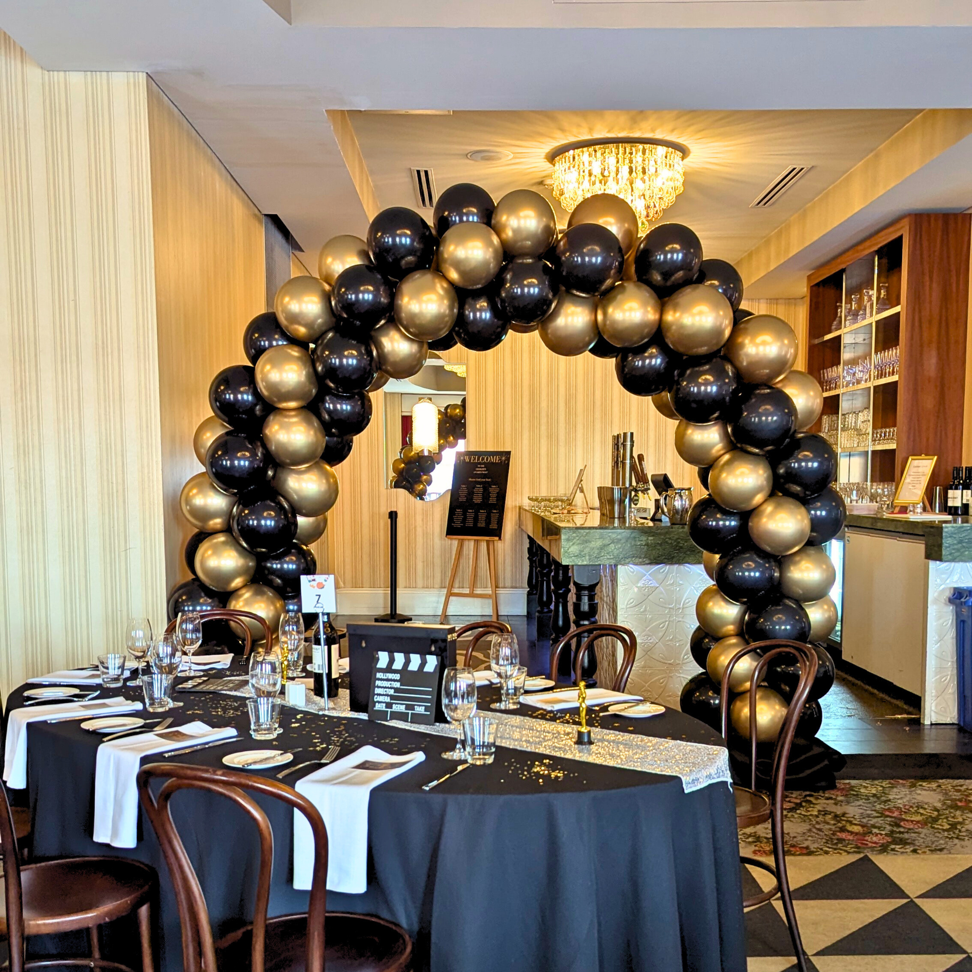 Decorative arch made of black and gold balloons in a banquet hall. corporate balloon arch Brisbane, branded balloon arch QLD, corporate event styling Brisbane, balloon arch for product launch, brand activation balloon display, media wall balloon arch Brisbane, conference balloon styling QLD, corporate event balloons Gold Coast, custom colour balloon arch Brisbane, business event balloon installation QLD