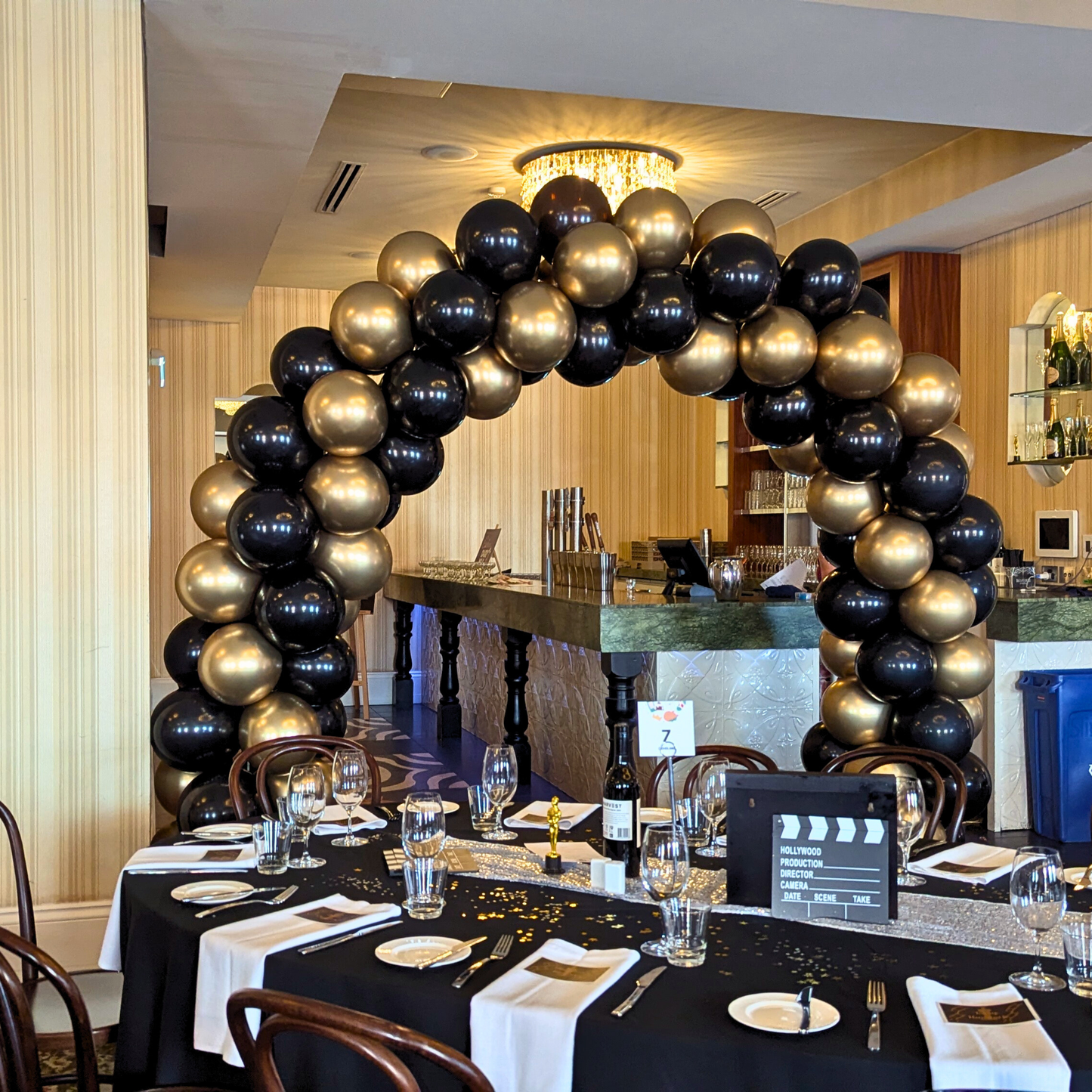 Decorative arch made of black and gold balloons in a banquet hall. corporate balloon arch Brisbane, branded balloon arch QLD, corporate event styling Brisbane, balloon arch for product launch, brand activation balloon display, media wall balloon arch Brisbane, conference balloon styling QLD, corporate event balloons Gold Coast, custom colour balloon arch Brisbane, business event balloon installation QLD