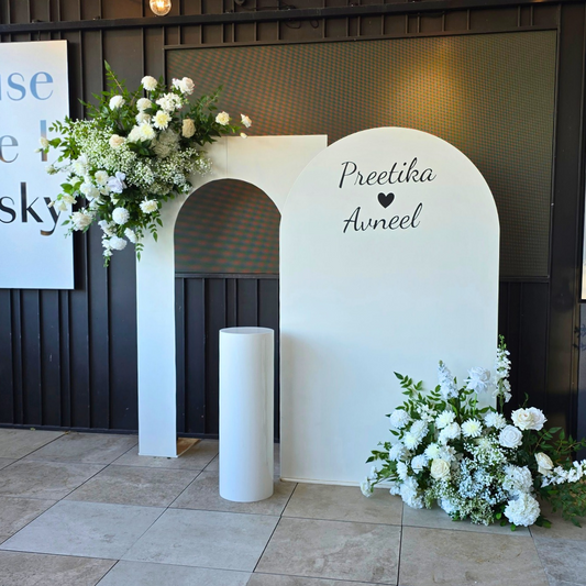 Decorative arch with floral arrangements and personalized name on a tiled floor. engagement party backdrop, floral engagement backdrop, romantic event styling, wedding decor hire, proposal backdrop hire, Brisbane event hire, elegant floral arch, custom event backdrop, pre-wedding decorations, luxe engagement party setup