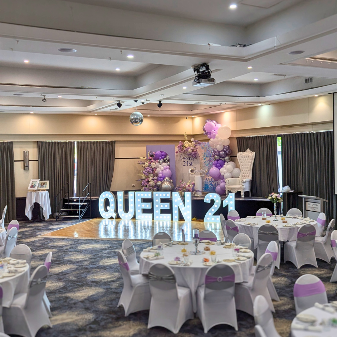 Purple, white silver floral and balloon backdrop with an iridescent shimmer wall. Signage says "Queen's 21st" with large LED lights. Prop hire, Prop hiring, Prop hire, event stylists Brisbane, brisbane event styling, brisbane event styling, event stylist Brisbane, Brisbane Wedding, Gold Coast Wedding, Floral Styling, Lush & Lavish Events, Brisbane Corporate Styling, Gold Coast Corporate Styling, Brisbane Brand Activation, Gold Coast Tablescapes, Brisbane Candle Hire