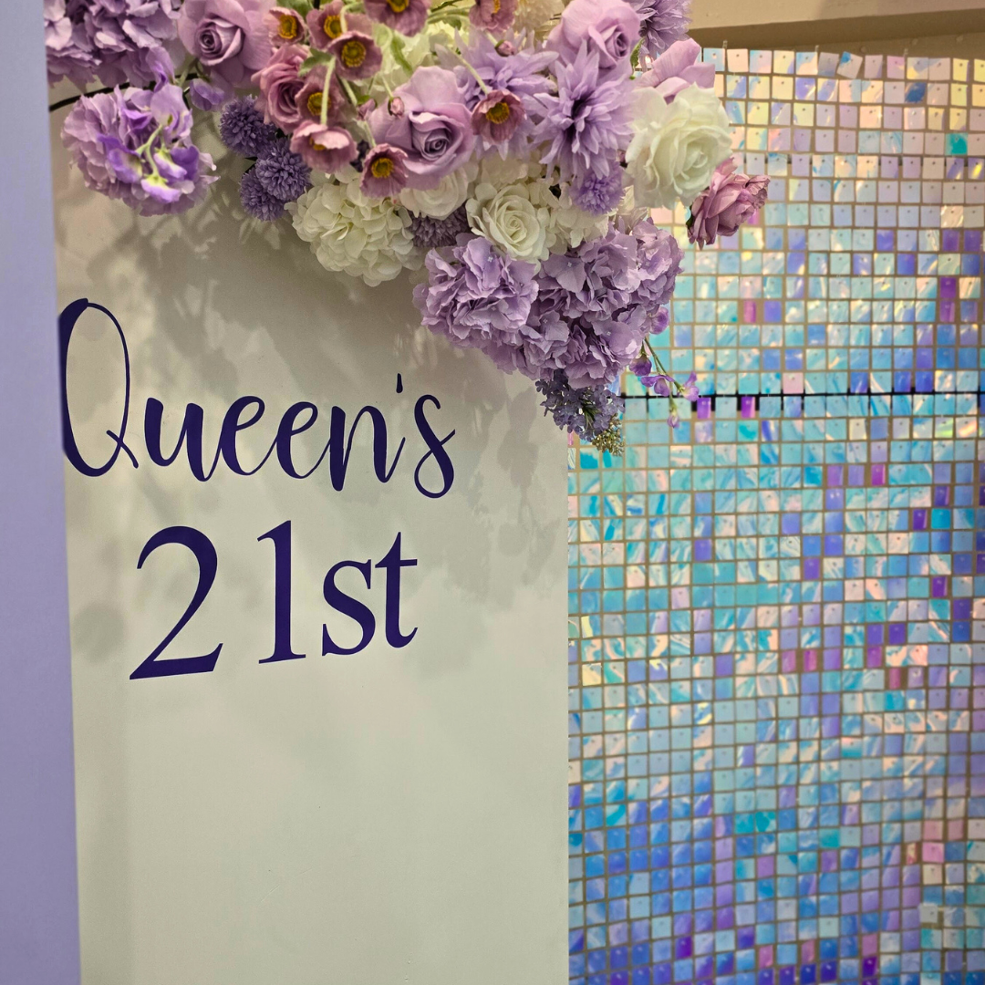 Purple, white silver floral and balloon backdrop with an iridescent shimmer wall. Signage says "Queen's 21st" with large LED lights. Prop hire, Prop hiring, Prop hire, event stylists Brisbane, brisbane event styling, brisbane event styling, event stylist Brisbane, Brisbane Wedding, Gold Coast Wedding, Floral Styling, Lush & Lavish Events, Brisbane Corporate Styling, Gold Coast Corporate Styling, Brisbane Brand Activation, Gold Coast Tablescapes, Brisbane Candle Hire