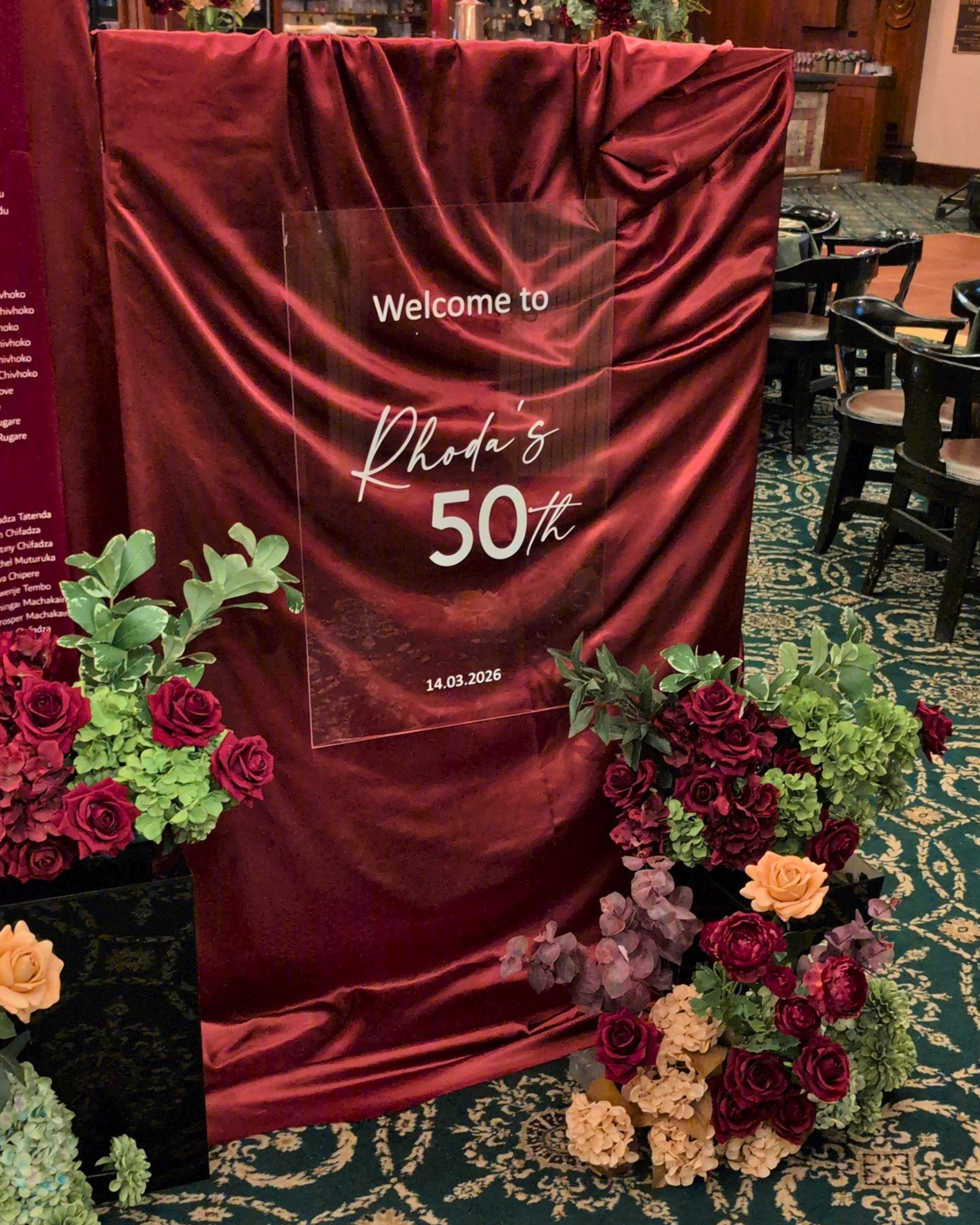 Decorative setup with red curtain, floral arrangements, and a sign for a 50th birthday celebration. brisbane event styling, brisbane event planner, brisbane on the day coordination, brisbane 50th birthday styling, luxury event styling brisbane, brisbane birthday event planner, event stylist brisbane australia, brisbane venue styling ideas, elegant birthday styling brisbane, brisbane event design services, corporate event styling brisbane, brisbane party stylist, moody event styling brisbane, brisbane event 