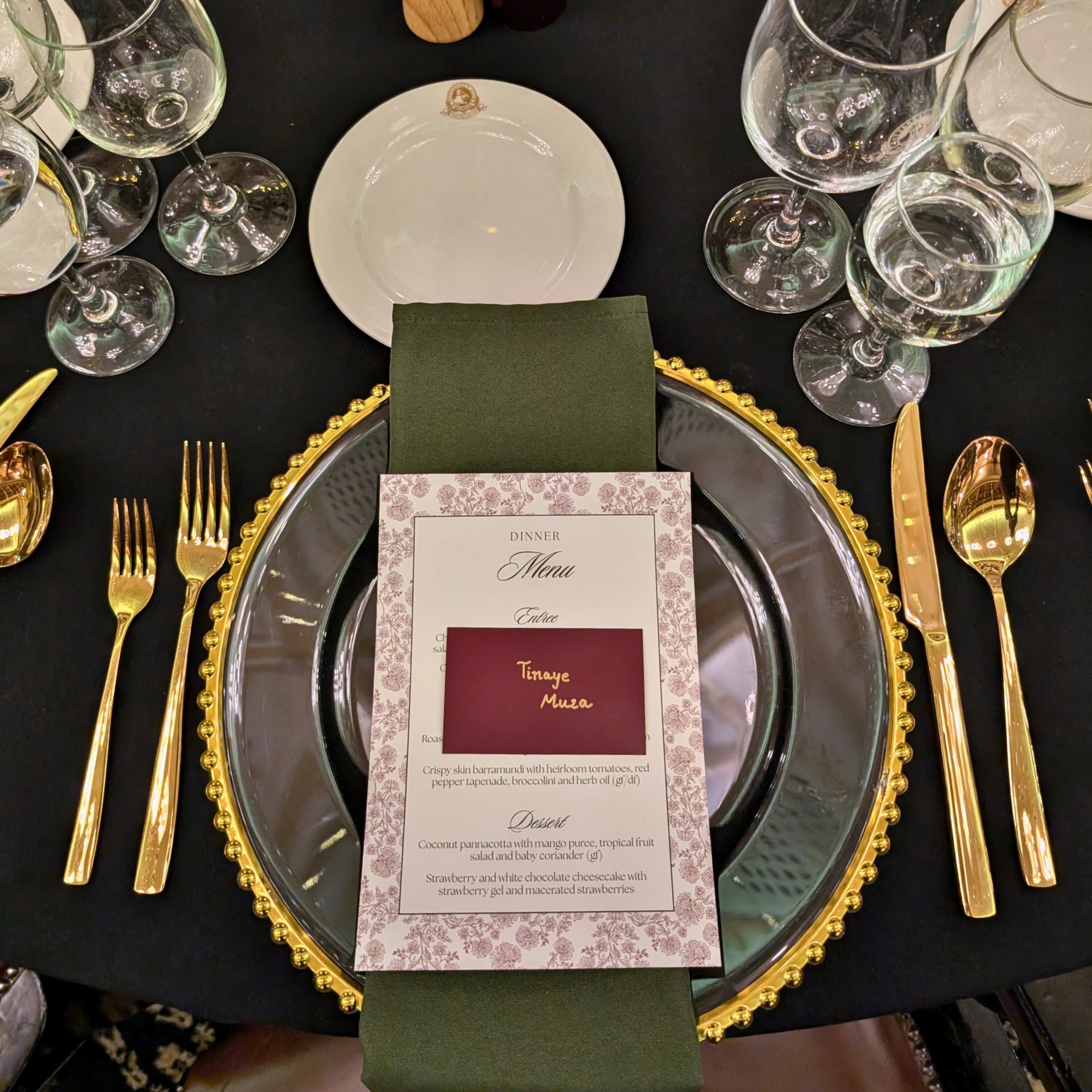 Dining table setting with gold cutlery, green napkin, and a menu card on a black tablecloth. brisbane event styling, brisbane event planner, brisbane on the day coordination, brisbane 50th birthday styling, luxury event styling brisbane, brisbane birthday event planner, event stylist brisbane australia, brisbane venue styling ideas, elegant birthday styling brisbane, brisbane event design services, corporate event styling brisbane, brisbane party stylist, moody event styling brisbane, brisbane event coordin