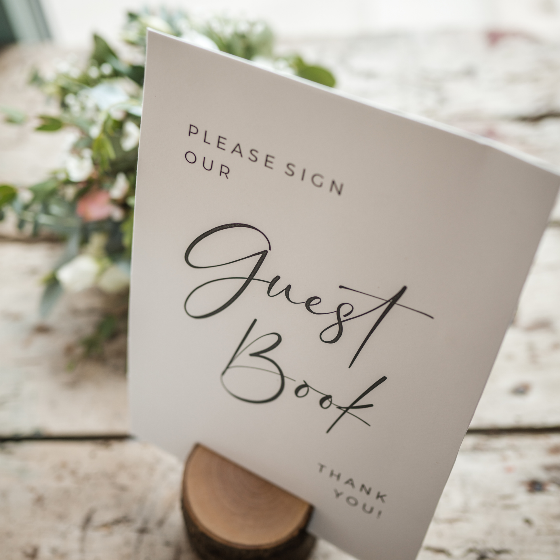 A white card with the words "Please Sign Our Guest Book" in elegant calligraphy sits on a wooden stand. The card also includes a "Thank You" message at the bottom. Prop hire, Prop hiring, Prop hire, event stylists Brisbane, brisbane event styling, brisbane event styling, event stylist Brisbane, Brisbane Wedding, Gold Coast Wedding, Floral Styling, Lush & Lavish Events, Brisbane Tablescape, Gold Coast Tablescapes, Brisbane Candle Hire