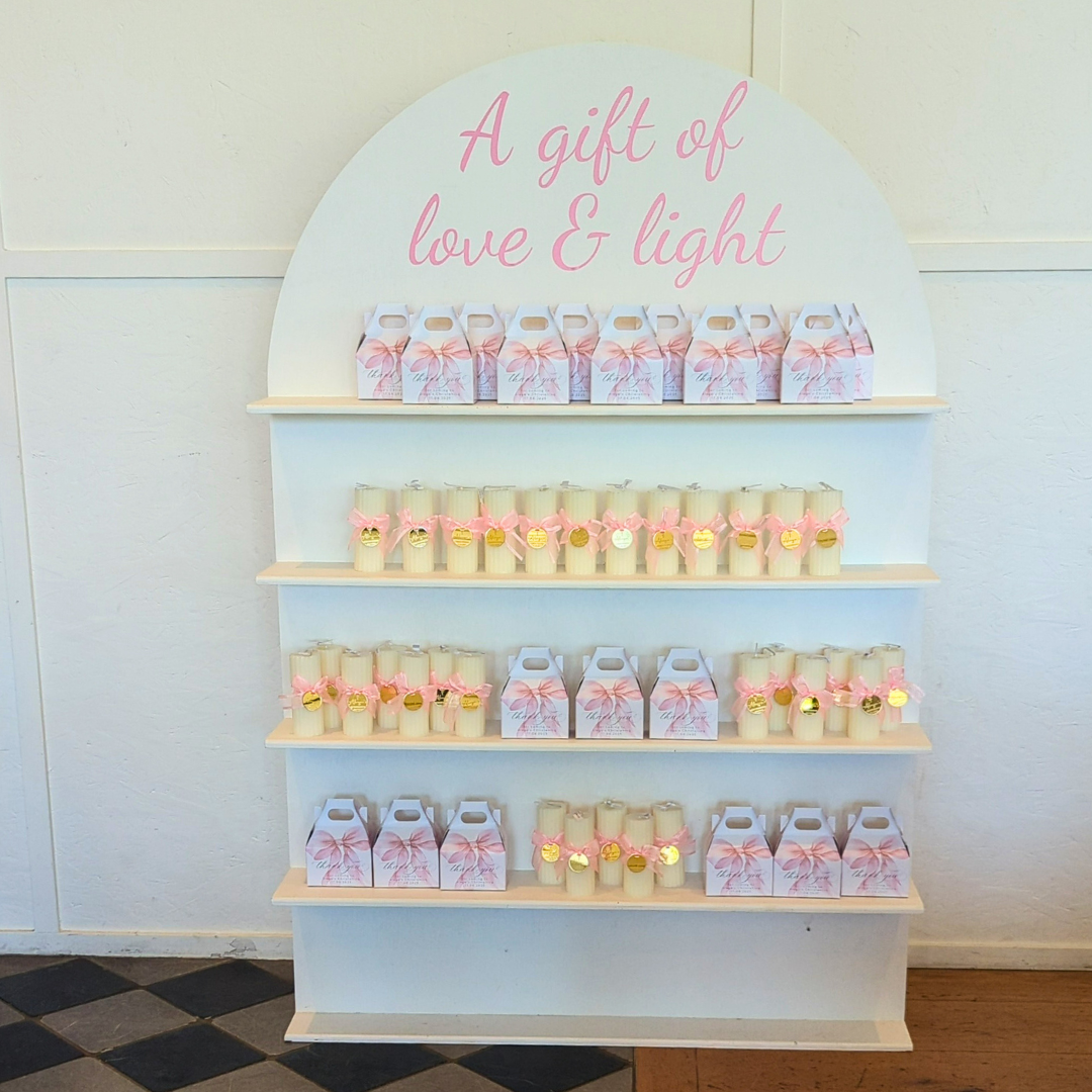 Display of candles and gift boxes with 'A gift of love & light' text on a white wall. Prop hire, Prop hiring, Prop hire, event stylists Brisbane, brisbane event styling, brisbane event styling, event stylist Brisbane, Brisbane Wedding, Gold Coast Wedding, Floral Styling, Lush & Lavish Events, Brisbane Corporate Styling, Gold Coast Corporate Styling, Brisbane Brand Activation, Gold Coast Tablescapes, Brisbane Candle Hire