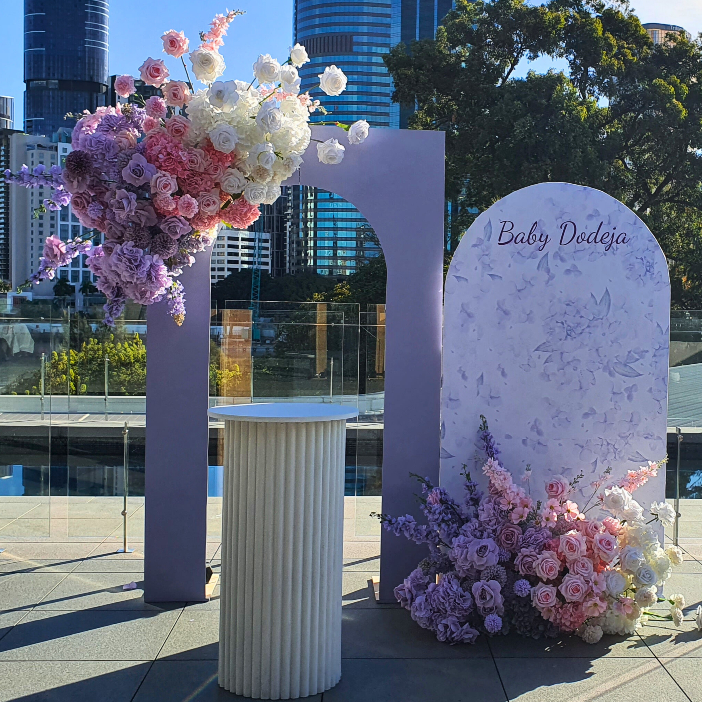 Floral arch with "Baby Dodeja" sign, white pedestal, and urban backdrop. Prop hire, Prop hiring, Prop hire, event stylists Brisbane, brisbane event styling, brisbane event styling, event stylist Brisbane, Brisbane Wedding, Gold Coast Wedding, Floral Styling, Lush & Lavish Events, Brisbane Corporate Styling, Gold Coast Corporate Styling, Brisbane Brand Activation
