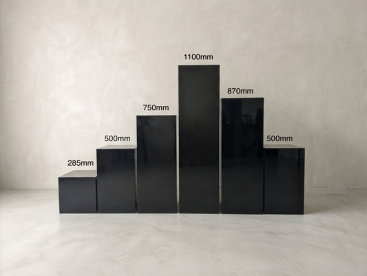 Six glossy black rectangular plinths in varied heights, labelled with their dimensions.