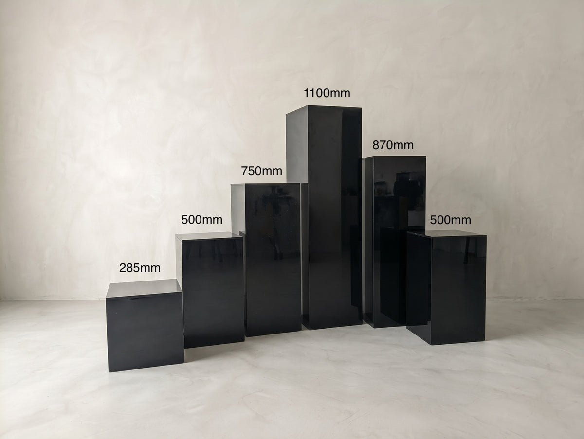 Six glossy black plinths grouped together, showing a range of labelled heights.