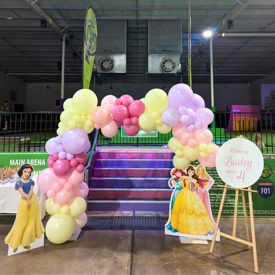 A balloon arch in pinks, purple and yellow, flanked with Disney Princess cut outs. Prop hire, Prop hiring, Prop hire, event stylists Brisbane, brisbane event styling, brisbane event styling, event stylist Brisbane, Brisbane Wedding, Gold Coast Wedding, Floral Styling, Lush & Lavish Events, Brisbane Corporate Styling, Gold Coast Corporate Styling, Brisbane Brand Activation, Gold Coast Tablescapes, Brisbane Candle Hire