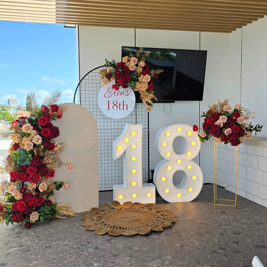 Floral backdrop in red, gold and green with large LED 18. Signage says Erin's 18th. Prop hire, Prop hiring, Prop hire, event stylists Brisbane, brisbane event styling, brisbane event styling, event stylist Brisbane, Brisbane Wedding, Gold Coast Wedding, Floral Styling, Lush & Lavish Events, Brisbane Corporate Styling, Gold Coast Corporate Styling, Brisbane Brand Activation, Gold Coast Tablescapes, Brisbane Candle Hire