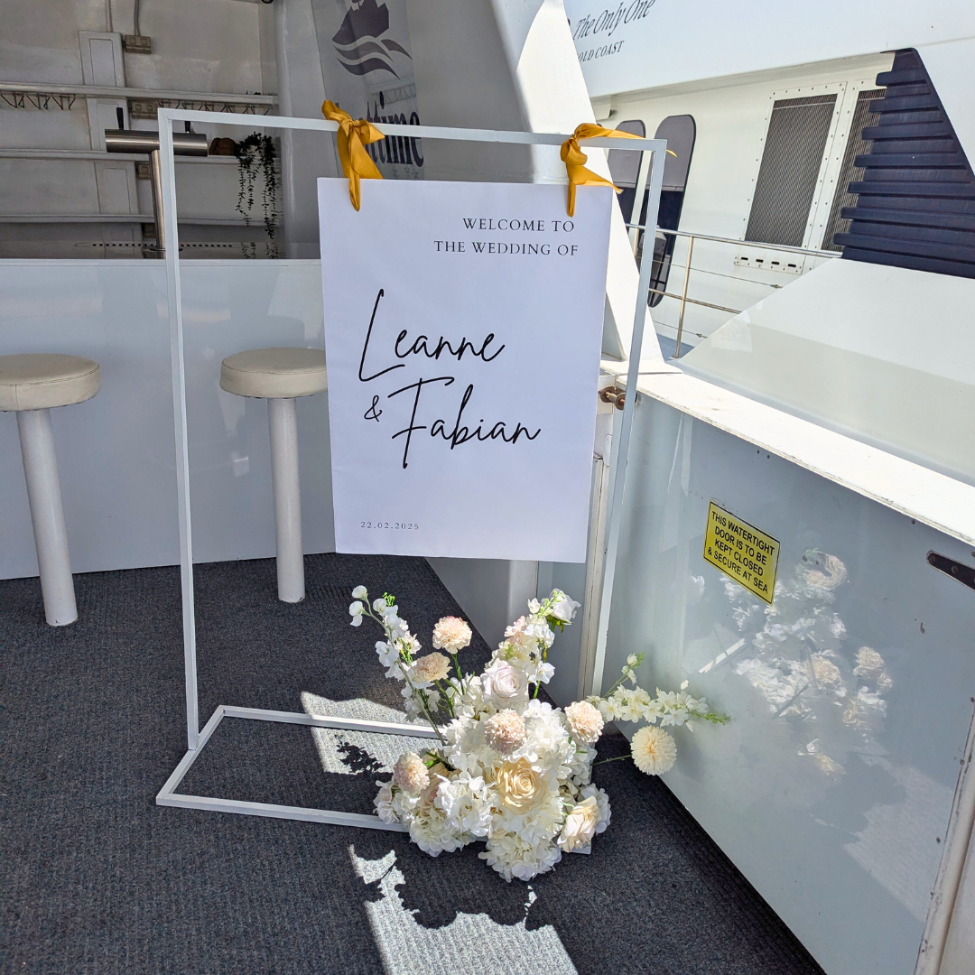Large frame welcome sign hire featuring a personalised A4 poster displayed on a white metal frame with elegant ribbons and a complementary floral arrangement. Perfect for weddings, engagement parties, baby showers, milestone birthdays, 18th and 21st birthday celebrations, kids parties and luxury event styling in Brisbane, Gold Coast and South East Queensland.