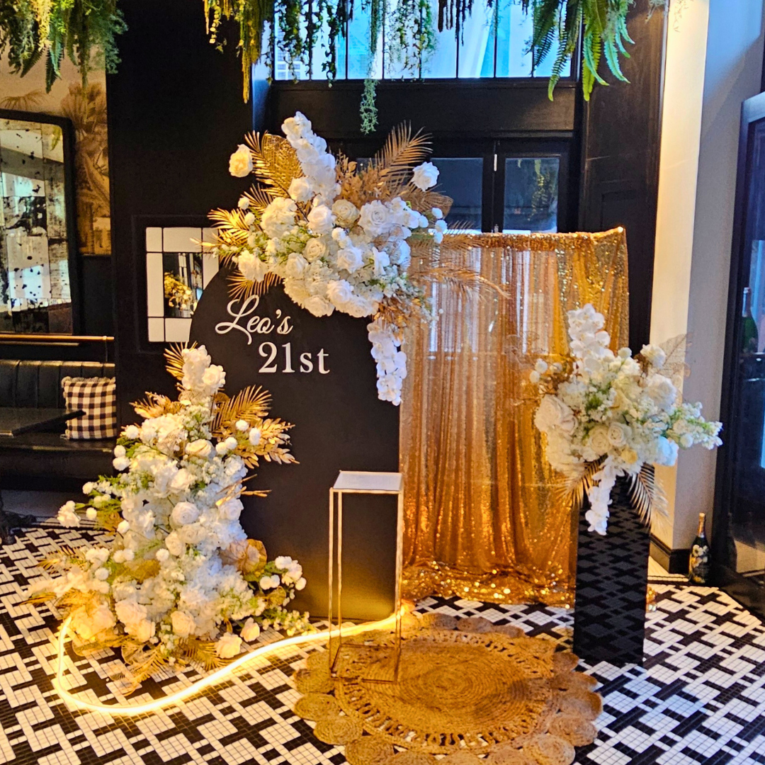 Decorative setup with flowers and a gold curtain for a 21st milestone birthday celebration. Prop hire, Prop hiring, Prop hire, event stylists Brisbane, brisbane event styling, brisbane event styling, event stylist Brisbane, Brisbane Wedding, Gold Coast Wedding, Floral Styling, Lush & Lavish Events, Brisbane Corporate Styling, Gold Coast Corporate Styling, Brisbane Brand Activation, Gold Coast Tablescapes, Brisbane Candle Hire