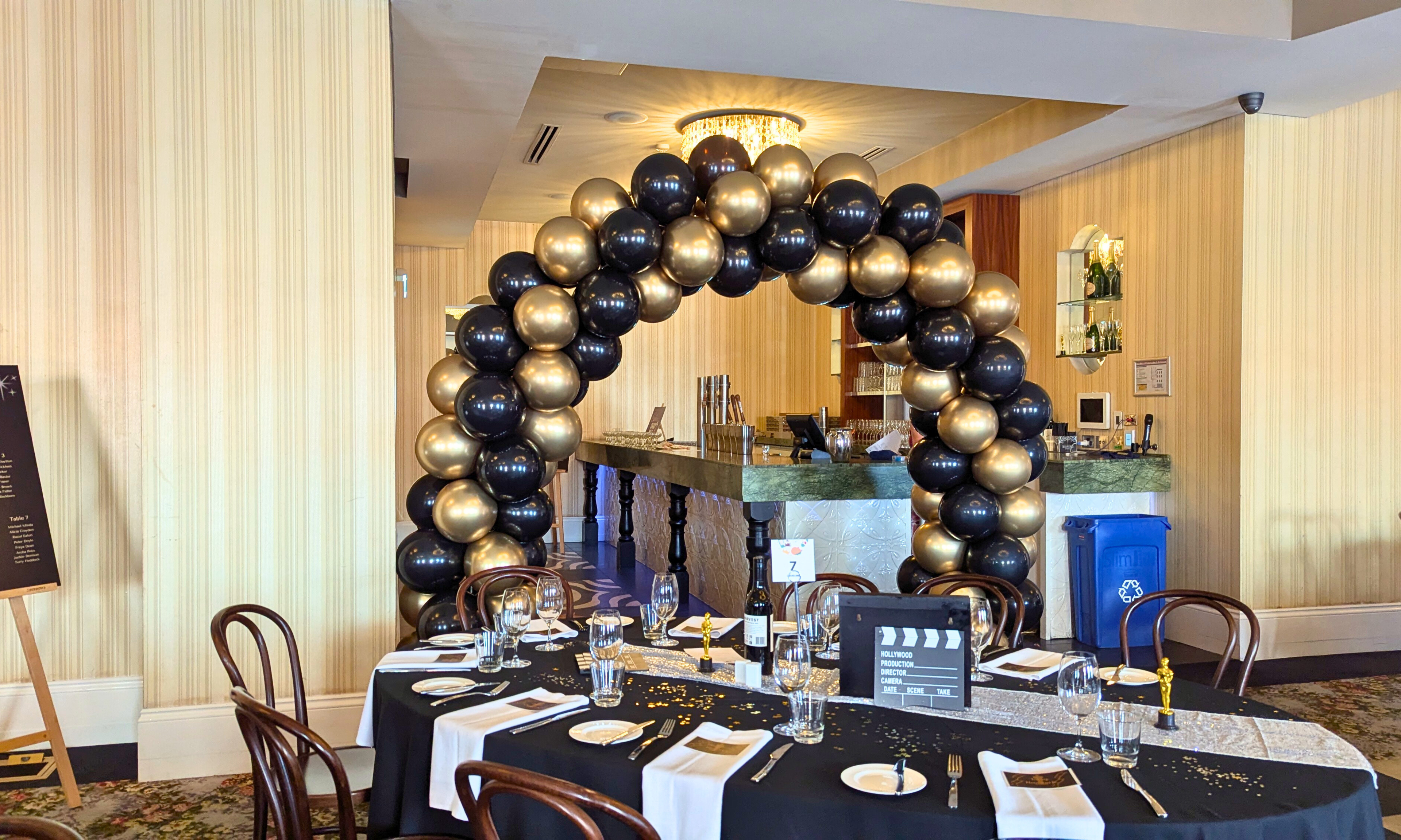 Decorative balloon arch in a banquet hall with table settings. monelez international spiral balloon arch