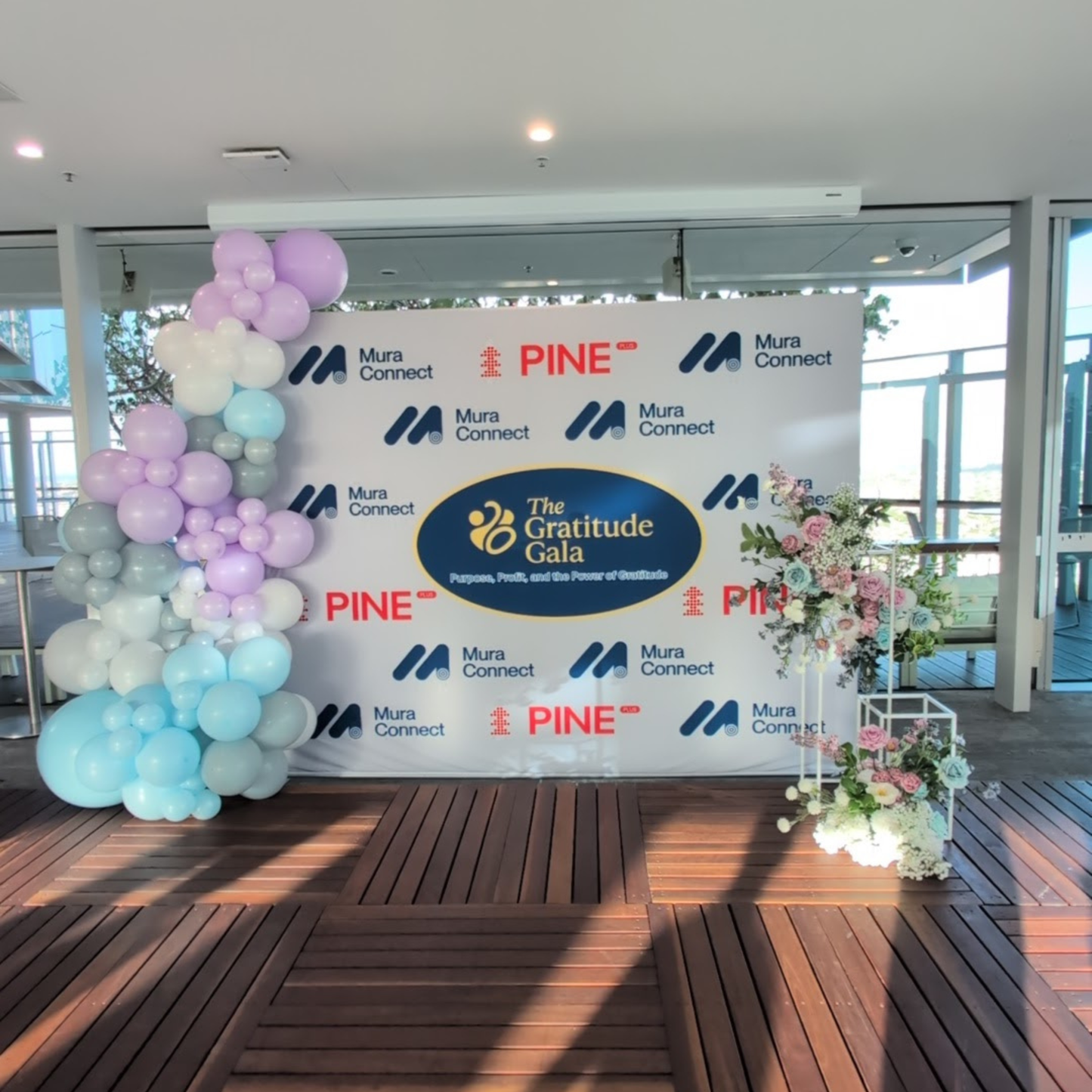 Backdrop with logos and balloons in a room with large windows. media wall balloon styling, balloon garland installation, corporate balloon styling, brand activation balloons, media wall styling service, campaign balloon install, branded event styling, product launch balloon decor, PR event styling balloons, corporate event decor hire, balloon installation service, event styling brisbane, balloon styling brisbane, corporate events brisbane, brand activation brisbane, event styling gold coast, balloon install