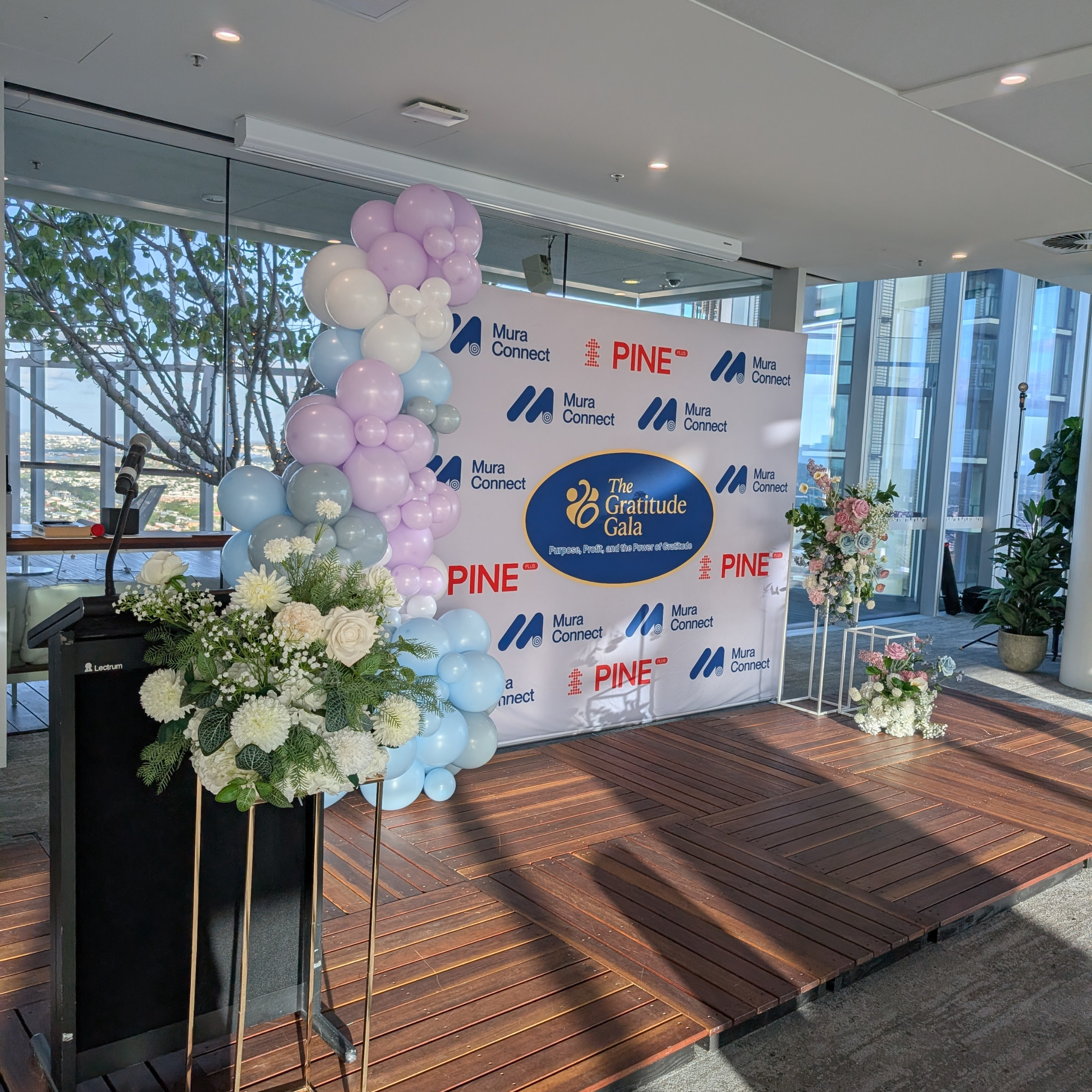 Decorated event setup with balloons, flowers, and a branded backdrop in an indoor setting. media wall balloon styling, balloon garland installation, corporate balloon styling, brand activation balloons, media wall styling service, campaign balloon install, branded event styling, product launch balloon decor, PR event styling balloons, corporate event decor hire, balloon installation service, event styling brisbane, balloon styling brisbane, corporate events brisbane, brand activation brisbane, event styling