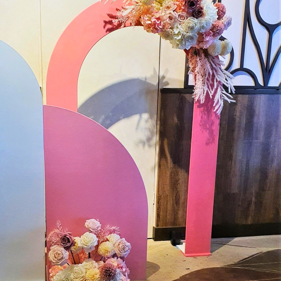 A pink and white floral engagement party backdrop featuring a large pink arch with floral arrangements, a white arch, and various decorative elements. Styled by Lush and Lavish Events in Brisbane.