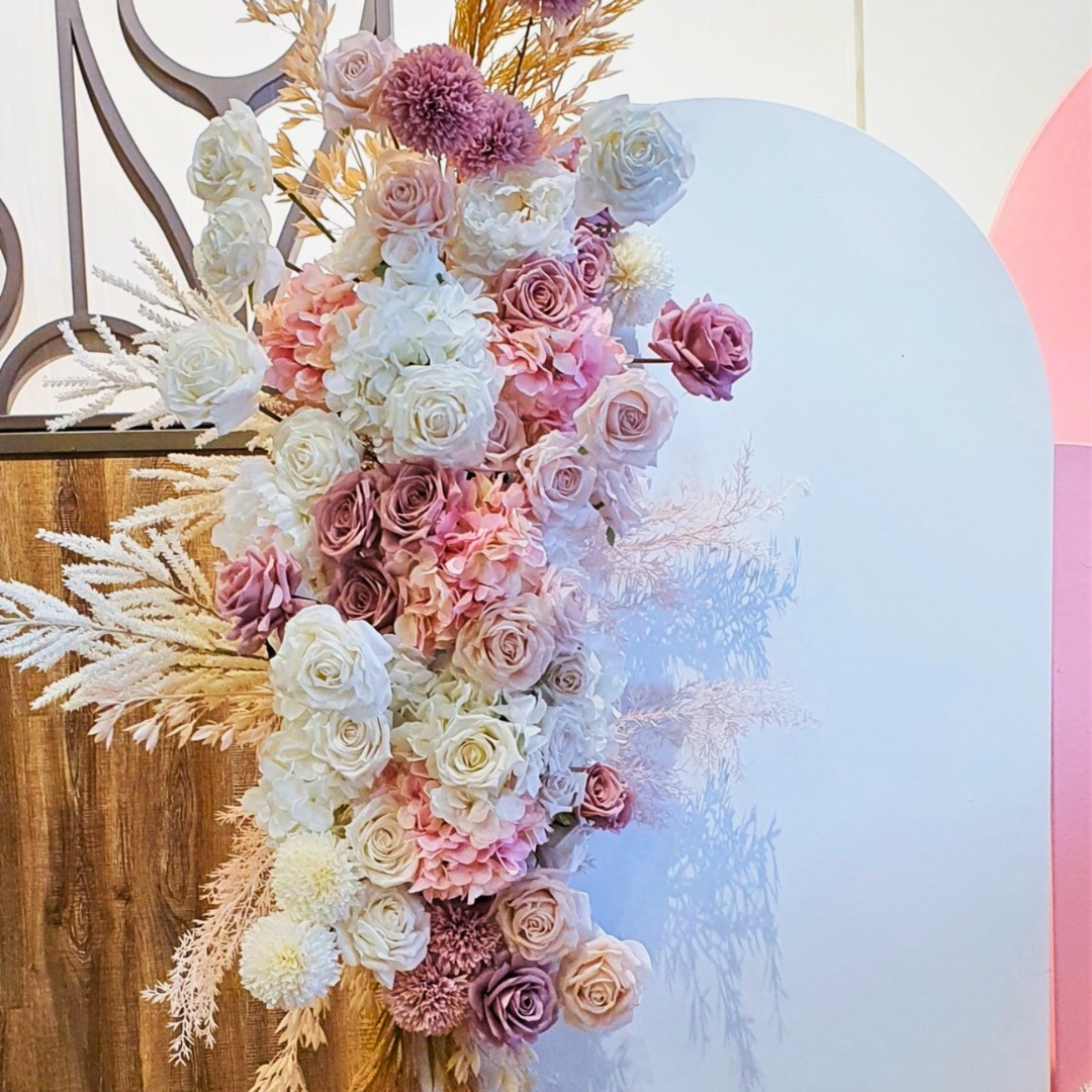 A pink and white floral engagement party backdrop featuring a large pink arch with floral arrangements, a white arch, and various decorative elements. Styled by Lush and Lavish Events in Brisbane.
