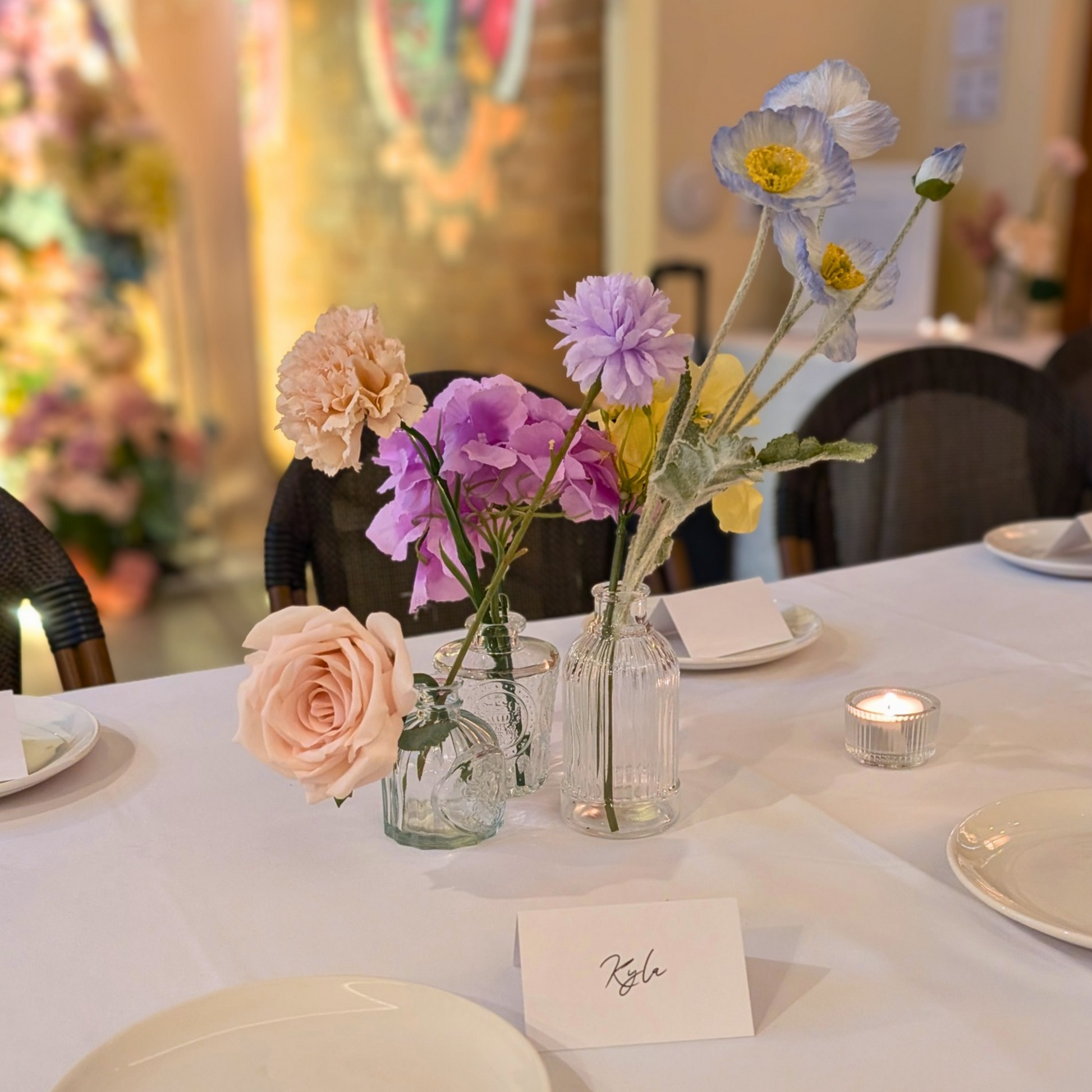 Decorative table setting with small vases of flowers on a black  tablecloth. reception table styling hire, guest table décor hire, wedding table decoration hire, faux bud vases hire, wedding flower décor hire, elegant table styling hire, wedding table centrepieces hire, Brisbane wedding décor hire, Gold Coast wedding décor hire, DIY wedding table styling, DIY reception table décor, DIY wedding centrepieces, DIY faux flower table styling, DIY wedding vases set, DIY wedding table décor Brisbane