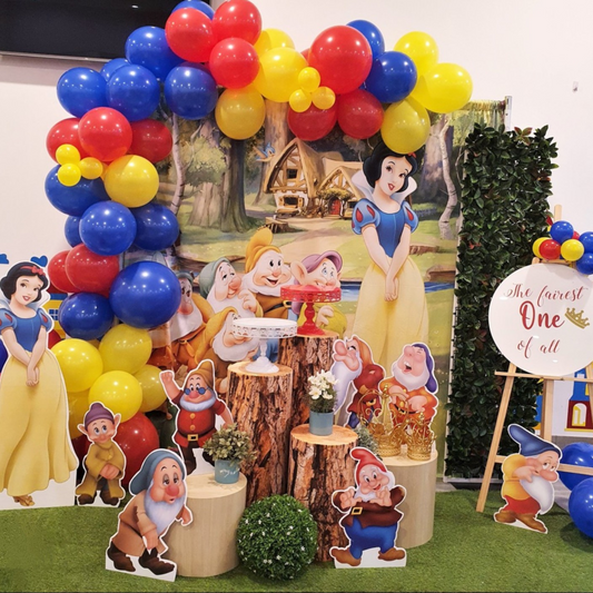 A colorful balloon arch and Snow White-themed backdrop create a magical party scene. Life-size cutouts of the Seven Dwarfs and a sign reading "The Fairest One of All" complete the fairytale setting. Prop hire, Prop hiring, Prop hire, event stylists Brisbane, brisbane event styling, brisbane event styling, event stylist Brisbane, Brisbane Wedding, Gold Coast Wedding, Floral Styling, Lush & Lavish Events, Brisbane Tablescape, Gold Coast Tablescapes, Brisbane Candle Hire