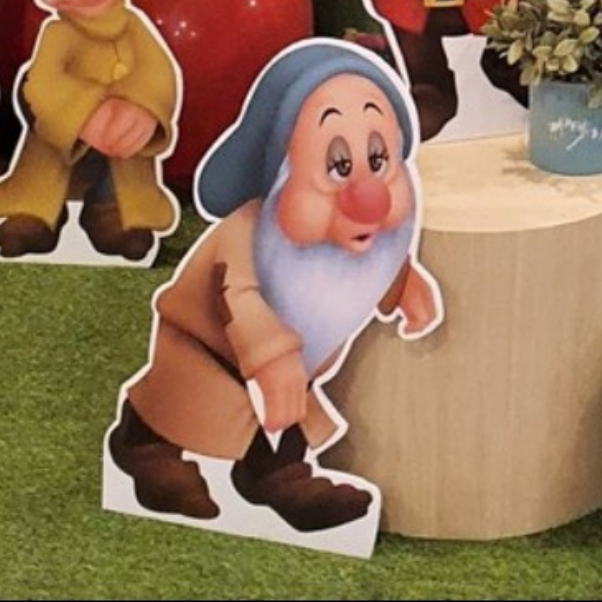 Cutout of a dwarf character from Snow White, positioned in front of colorful balloons with a blurred background, ideal for themed parties or events. Prop hire, Prop hiring, Prop hire, event stylists Brisbane, brisbane event styling, brisbane event styling, event stylist Brisbane, Brisbane Wedding, Gold Coast Wedding, Floral Styling, Lush & Lavish Events, Brisbane Tablescape, Gold Coast Tablescapes, Brisbane Candle Hire