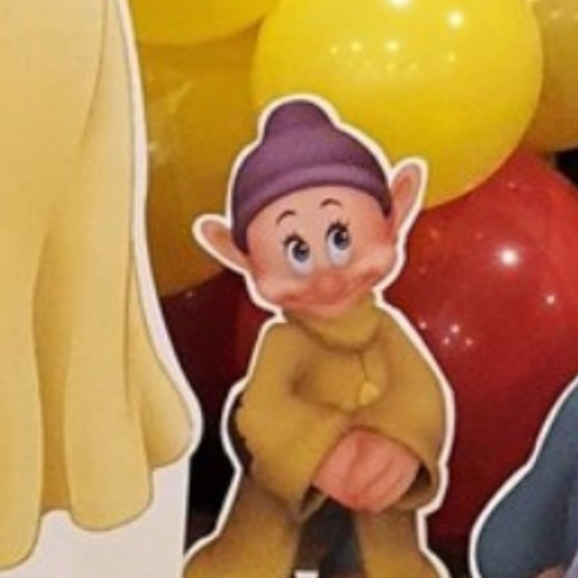 Cutout of a dwarf character from Snow White, positioned in front of colorful balloons with a blurred background, ideal for themed parties or events. Prop hire, Prop hiring, Prop hire, event stylists Brisbane, brisbane event styling, brisbane event styling, event stylist Brisbane, Brisbane Wedding, Gold Coast Wedding, Floral Styling, Lush & Lavish Events, Brisbane Tablescape, Gold Coast Tablescapes, Brisbane Candle Hire